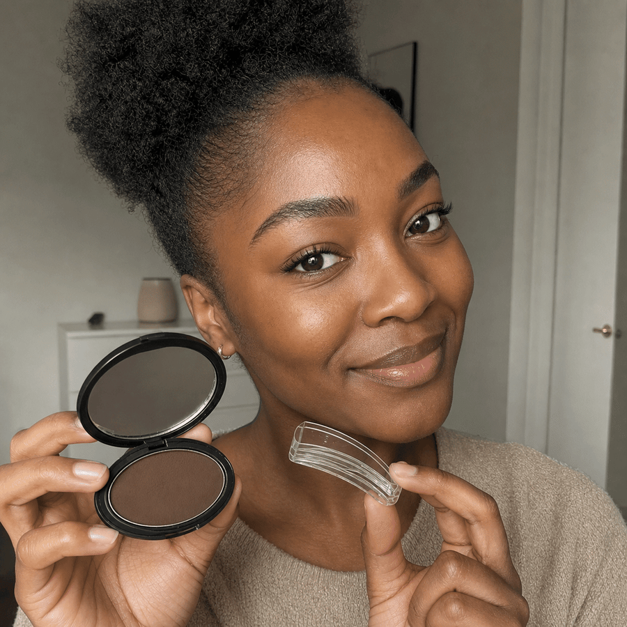 Customer holding the MYBROWS brow stamp kit up to her brow
